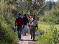 Polling officials along with Indian policemen walk in the interiors of Dal Lake towards their designated polling station after collecting el...