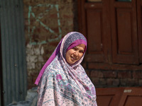 A woman looks on as polling officials and Indian policemen walk in the interiors of Dal Lake towards their designated polling station after...