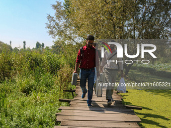 Polling officials walk in the interiors of Dal Lake towards their designated polling station after collecting election materials at a distri...