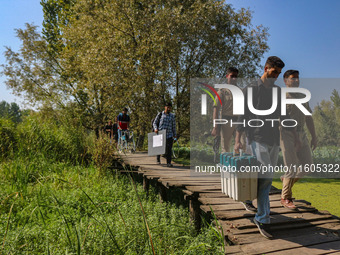 Polling officials along with Indian policemen walk in the interiors of Dal Lake towards their designated polling station after collecting el...