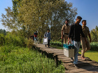 Polling officials along with Indian policemen walk in the interiors of Dal Lake towards their designated polling station after collecting el...