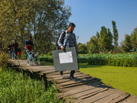 Polling officials walk in the interiors of Dal Lake towards their designated polling station after collecting election materials at a distri...