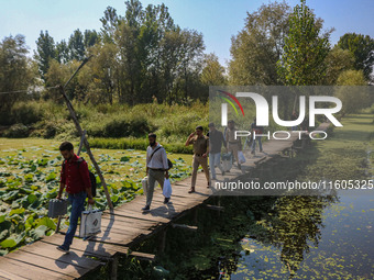 Polling officials along with Indian policemen walk in the interiors of Dal Lake towards their designated polling station after collecting el...