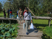 Polling officials along with Indian policemen walk in the interiors of Dal Lake towards their designated polling station after collecting el...