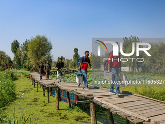 Polling officials walk in the interiors of Dal Lake towards their designated polling station after collecting election materials at a distri...