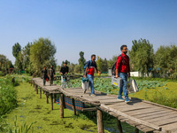 Polling officials walk in the interiors of Dal Lake towards their designated polling station after collecting election materials at a distri...