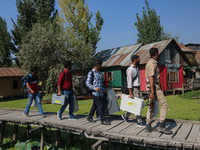 Polling officials, along with an Indian policeman, walk in the interiors of Dal Lake towards their designated polling station after collecti...