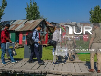 Polling officials along with Indian policemen walk in the interiors of Dal Lake towards their designated polling station after collecting el...