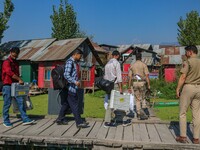 Polling officials along with Indian policemen walk in the interiors of Dal Lake towards their designated polling station after collecting el...