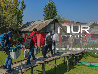 Polling officials, along with an Indian policeman, walk in the interiors of Dal Lake towards their designated polling station after collecti...