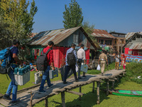 Polling officials, along with an Indian policeman, walk in the interiors of Dal Lake towards their designated polling station after collecti...