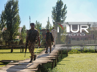 Indian police and paramilitary soldiers walk in the interiors of Dal Lake towards their designated polling station after collecting election...