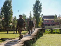 Indian police and paramilitary soldiers walk in the interiors of Dal Lake towards their designated polling station after collecting election...