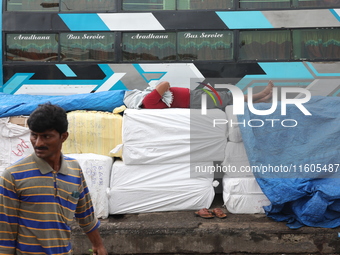 A laborer takes a nap before he loads consumer goods onto a passenger bus after it arrives from a neighboring state at a bus terminal in Kol...