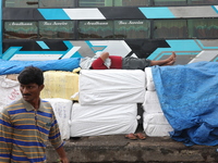 A laborer takes a nap before he loads consumer goods onto a passenger bus after it arrives from a neighboring state at a bus terminal in Kol...