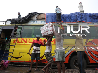 Labourers load consumer goods onto a passenger bus after it arrives from a neighboring state at a bus terminal in Kolkata, India, on Septemb...