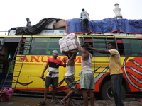 Labourers load consumer goods onto a passenger bus after it arrives from a neighboring state at a bus terminal in Kolkata, India, on Septemb...