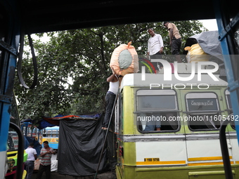 Labourers load consumer goods onto a passenger bus after it arrives from a neighboring state at a bus terminal in Kolkata, India, on Septemb...