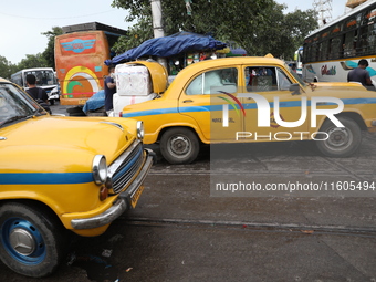 A unloads consumer goods from a yellow Ambassador taxi boot to load a bus after it arrives from a neighboring state at a bus terminal in Kol...