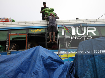 Labourers load sacks filled with sweet lime fruits onto a passenger bus after it arrives from a neighboring state at a bus terminal in Kolka...