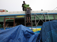 Labourers load sacks filled with sweet lime fruits onto a passenger bus after it arrives from a neighboring state at a bus terminal in Kolka...