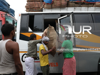 Labourers load consumer goods onto a passenger bus after it arrives from a neighboring state at a bus terminal in Kolkata, India, on Septemb...