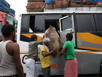 Labourers load consumer goods onto a passenger bus after it arrives from a neighboring state at a bus terminal in Kolkata, India, on Septemb...