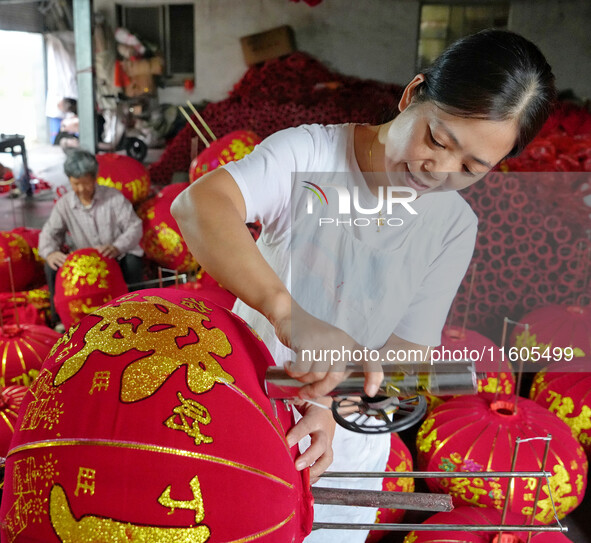 A worker makes red lanterns at a lantern processing workshop in Hai'an, China, on September 24, 2024. 