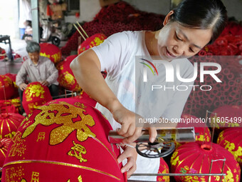 A worker makes red lanterns at a lantern processing workshop in Hai'an, China, on September 24, 2024. (