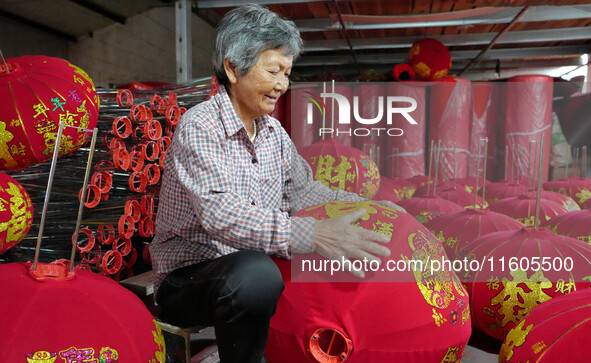 A worker makes red lanterns at a lantern processing workshop in Hai'an, China, on September 24, 2024. 