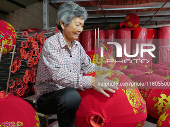 A worker makes red lanterns at a lantern processing workshop in Hai'an, China, on September 24, 2024. (