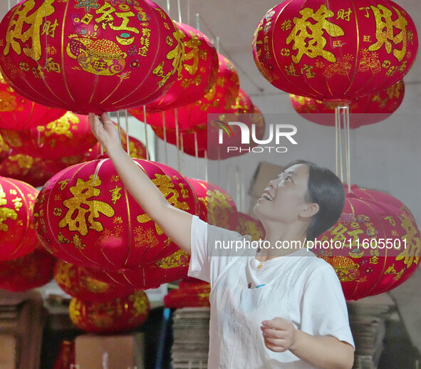 A worker makes red lanterns at a lantern processing workshop in Hai'an, China, on September 24, 2024. 