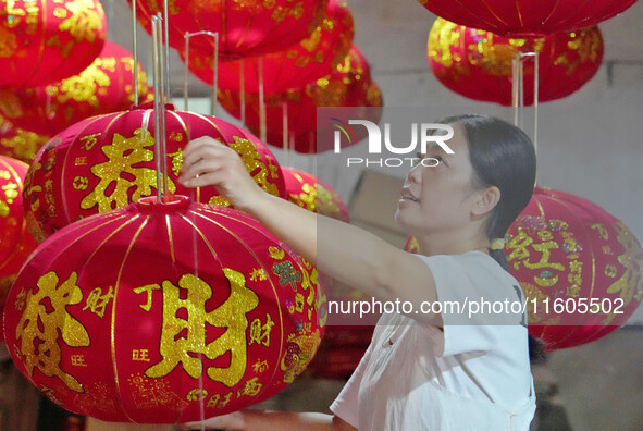 A worker makes red lanterns at a lantern processing workshop in Hai'an, China, on September 24, 2024. 