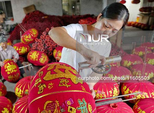 A worker makes red lanterns at a lantern processing workshop in Hai'an, China, on September 24, 2024. 