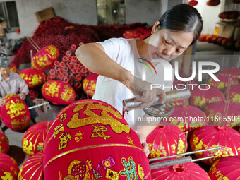 A worker makes red lanterns at a lantern processing workshop in Hai'an, China, on September 24, 2024. (