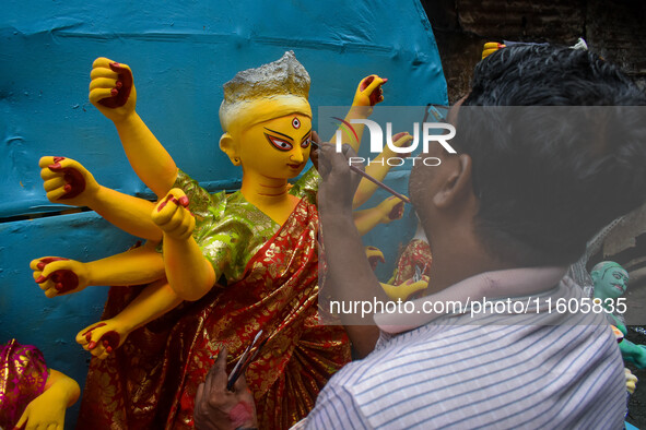 Artists paint the eyes of an idol of Goddess Durga, known as ''Chokhhu Daan,'' at a potters' hub ahead of the Durga Puja festival in Kolkata...