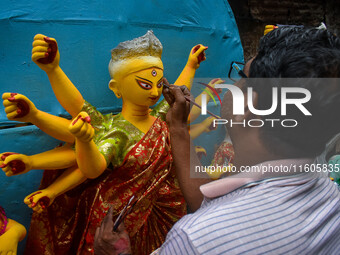 Artists paint the eyes of an idol of Goddess Durga, known as ''Chokhhu Daan,'' at a potters' hub ahead of the Durga Puja festival in Kolkata...