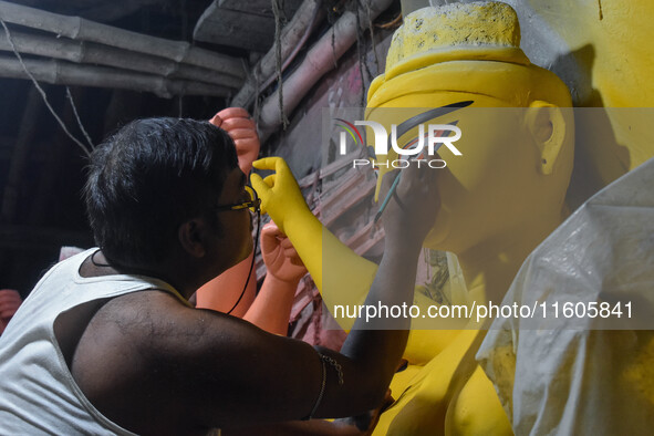 Artists paint the eyes of an idol of Goddess Durga, known as ''Chokhhu Daan,'' at a potters' hub ahead of the Durga Puja festival in Kolkata...