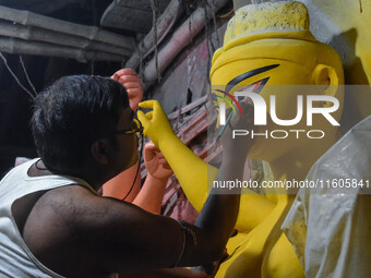 Artists paint the eyes of an idol of Goddess Durga, known as ''Chokhhu Daan,'' at a potters' hub ahead of the Durga Puja festival in Kolkata...