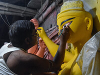 Artists paint the eyes of an idol of Goddess Durga, known as ''Chokhhu Daan,'' at a potters' hub ahead of the Durga Puja festival in Kolkata...