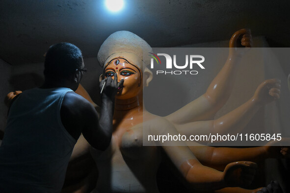 Artists paint the eyes of an idol of Goddess Durga, known as ''Chokhhu Daan,'' at a potters' hub ahead of the Durga Puja festival in Kolkata...