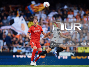 Dani Gomez (L) of Valencia CF competes for the ball with Herrando of CA Osasuna during the LaLiga EA Sports match between Valencia CF and CA...