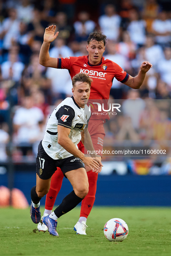 Dani Gomez (L) of Valencia CF competes for the ball with Herrando of CA Osasuna during the LaLiga EA Sports match between Valencia CF and CA...