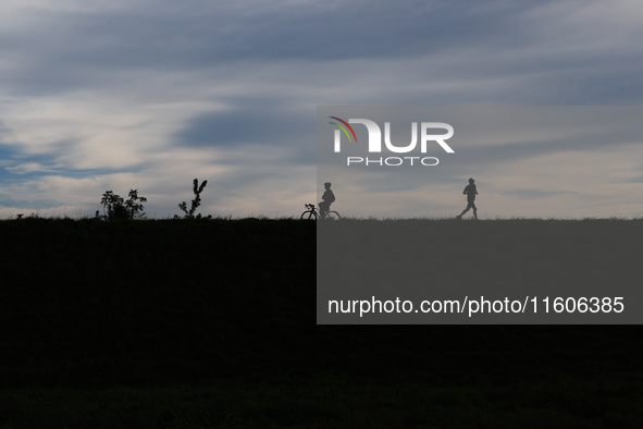 Cyclist and runner are seen at the flood embankment in Krakow, Poland on September 23, 2024. 