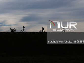 Cyclist and runner are seen at the flood embankment in Krakow, Poland on September 23, 2024. (