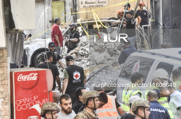 Security forces and medical teams arrive in the area after the Israeli army targets the 4th and 5th floors of a building in the Ghobeiry mun...