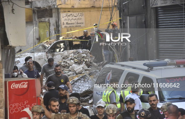 Security forces and medical teams arrive in the area after the Israeli army targets the 4th and 5th floors of a building in the Ghobeiry mun...