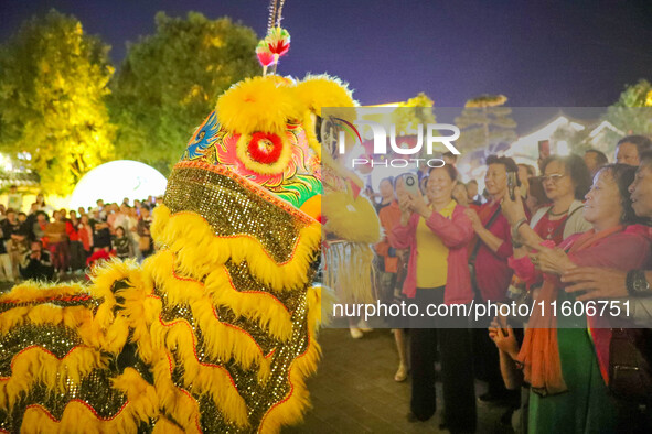 Tourists watch a lion dance performance at the ancient town of Xunxian in Hebi, China, on September 24, 2024. 