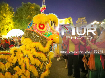 Tourists watch a lion dance performance at the ancient town of Xunxian in Hebi, China, on September 24, 2024. (