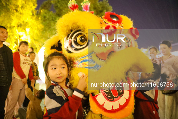 Children pose for a photo with lion dancers at the ancient town of Xunxian in Hebi, China, on September 24, 2024. 